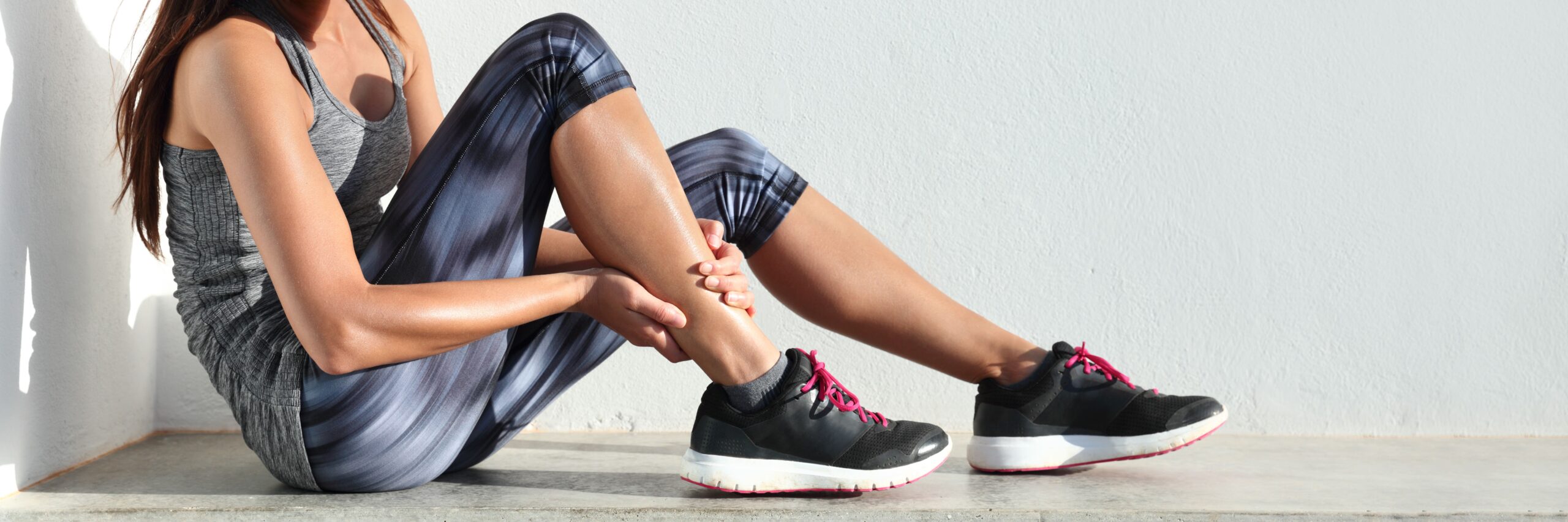 mujer sujetándose la pierna después de lesión deportiva